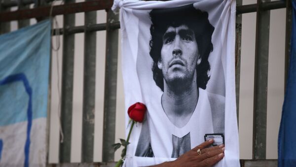 A rose is placed next to a banner of Argentine soccer great Diego Maradona as fans gather to mourn his death, at the Obelisk of Buenos Aires, Argentina November 25, 2020 - Sputnik Afrique