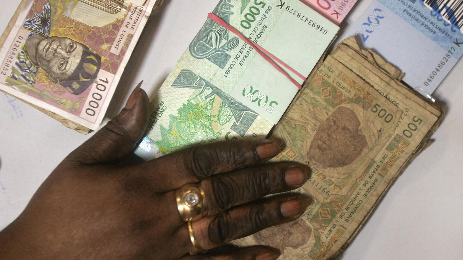 Une caissière de banque compte des piles de nouveaux billets de banque en francs CFA d'Afrique de l'Ouest ainsi que des billets de 500 CFA à l'ancienne, en bas à droite, et des billets de 10 000 CFA à l'ancienne, en haut à gauche, dans une banque de Dakar, au Sénégal, le lundi 13 septembre 2004. L'Afrique occidentale française est engagée dans une campagne massive regroupant huit pays pour retirer plus d'un milliard d'euros (dollars) en monnaie vieillie et molle. Une caissière de banque compte des piles de nouveaux billets de banque en francs CFA d'Afrique de l'Ouest ainsi que des billets de 500 CFA à l'ancienne, en bas à droite, et des billets de 10 000 CFA à l'ancienne, en haut à gauche, dans une banque de Dakar, au Sénégal, le lundi 13 septembre 2004. L'Afrique occidentale française est engagée dans une campagne massive regroupant huit pays pour retirer plus d'un milliard d'euros (dollars) en monnaie vieillie et molle. - Sputnik Afrique, 1920, 06.10.2024