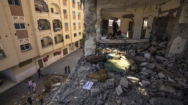 Palestinians look at destruction after an Israeli strike on the Gaza Strip in Khan Younis, Saturday, Nov. 18, 2023. (AP Photo/Fatima Shbair) - Sputnik Africa