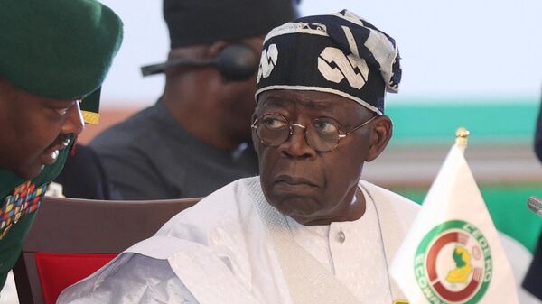 Nigerian President Bola Tinubu (R) speaks with his aide during the 64th Economic Community of West African States (ECOWAS) Head of States and Government ordinary session in Abuja on December 10, 2023. - Sputnik Africa