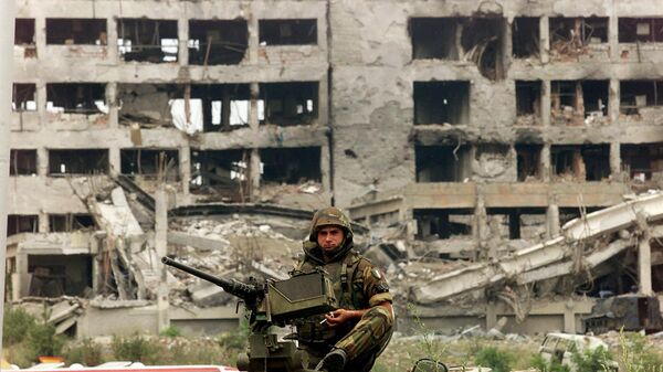 An Italian KFOR soldier mans a machine gun atop an armored vehicle in front of the NATO destroyed Serbian police headquarters at the entrance to the western Kosovo town of Djakovica 09 July, 1999. - Sputnik Africa