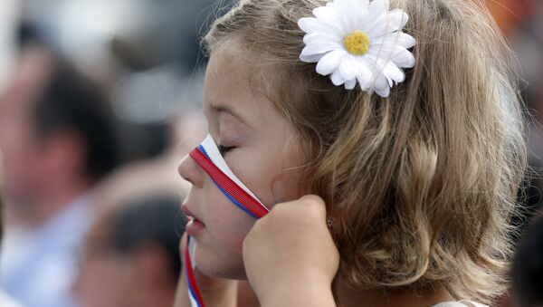 A girl plays with a ribbon in the colors of the Russian flag as she waits to see Russian President Vladimir Putin at the 2015 Expo, in Rho, near Milan, Italy, Wednesday, June 10, 2015 - Sputnik Afrique