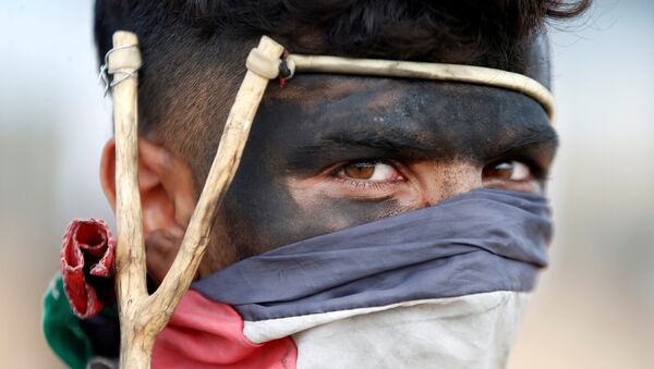 A Palestinian demonstrator with a slingshot looks on during a protest against U.S. embassy move to Jerusalem and ahead of the 70th anniversary of Nakba, at the Israel-Gaza border, east of Gaza City May 14, 2018. - Sputnik Afrique